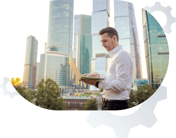 Image of man in front of tall office buildings on his laptop